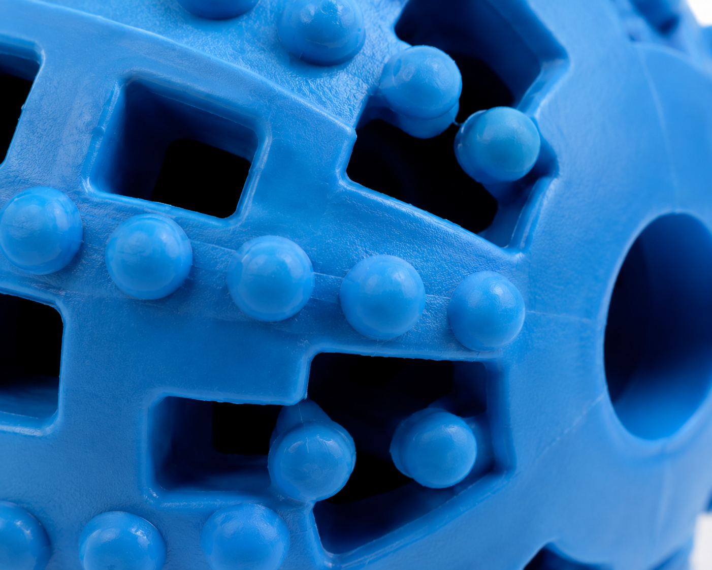 Close-up view of a textured blue plastic toy ball with various shapes and bumps Interactive Treat Dispensing Ball Toy for Dogs and Puppies - Image 2
